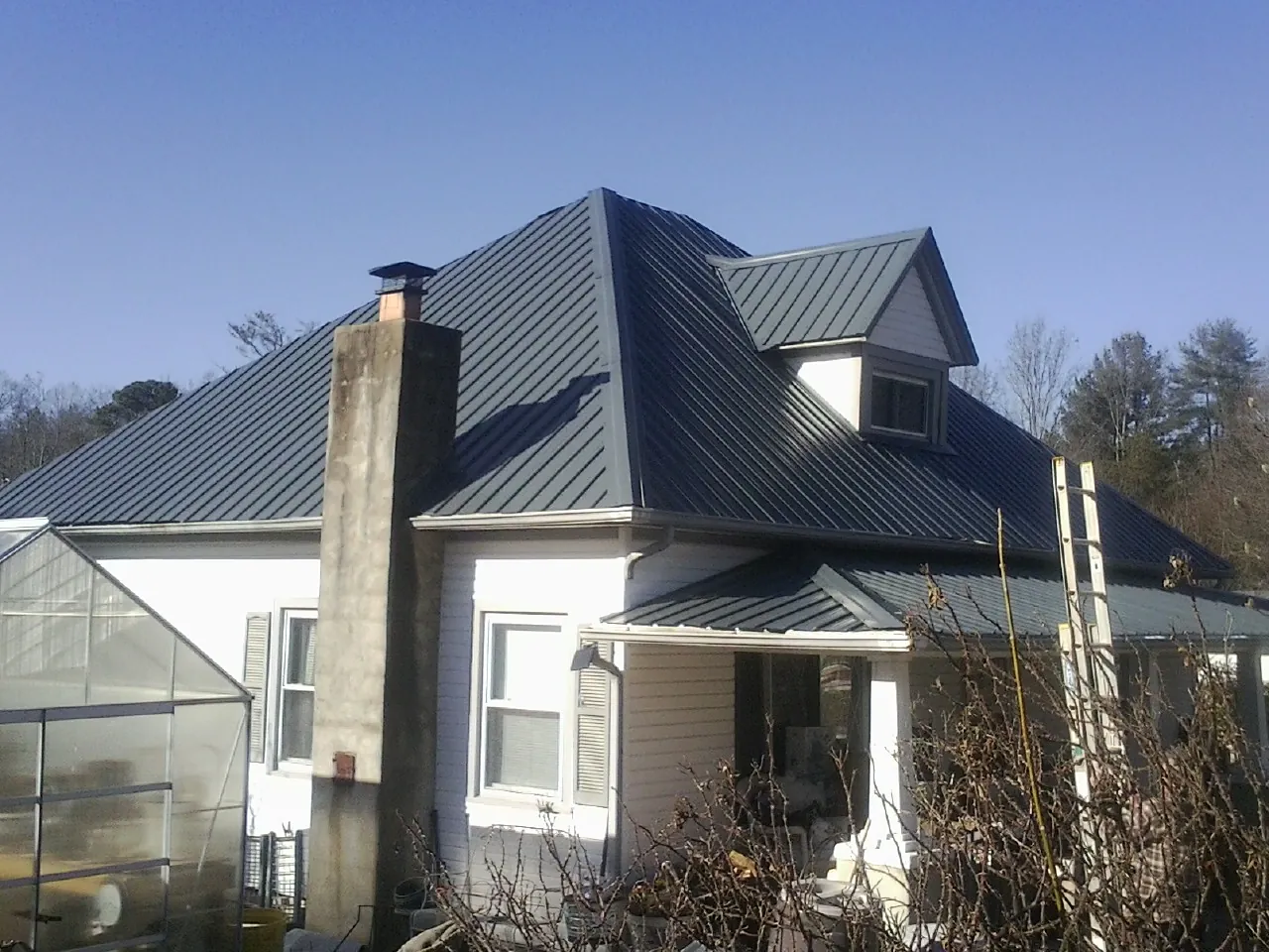 Dark blue standing seam metal roof on a white farmhouse with dormer — Slate & Tile Roof Repair by Roofing Brothers in Amador City