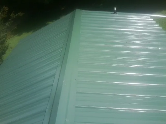 New green metal panels meeting at the ridge of a roof — Flat Roof Repair work by our crew in Amador City