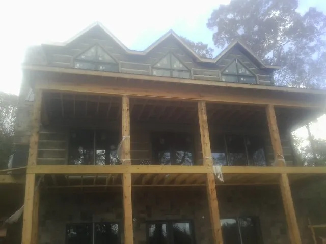 Dormers and porch framing on a large log home under construction — Roof Coating work by our crew in Amador City