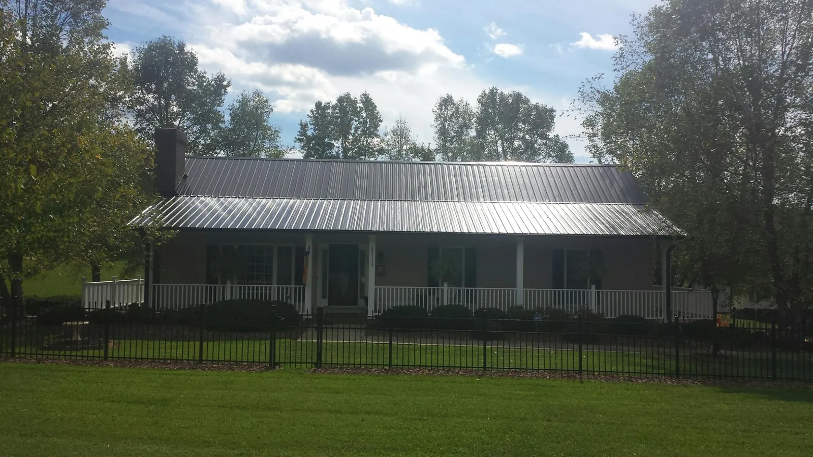 Gray metal roof on a brick ranch with a full width front porch — Gutter Guard Installation work by our crew in Amador City