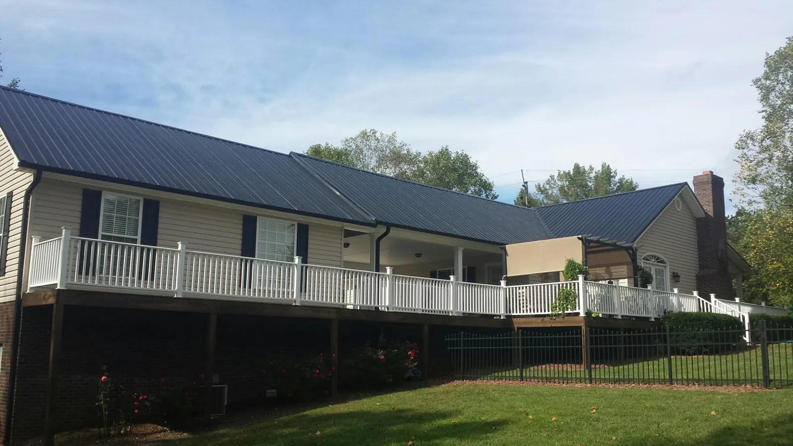 Black metal roof above a long white railed deck on a hillside home in Amador City