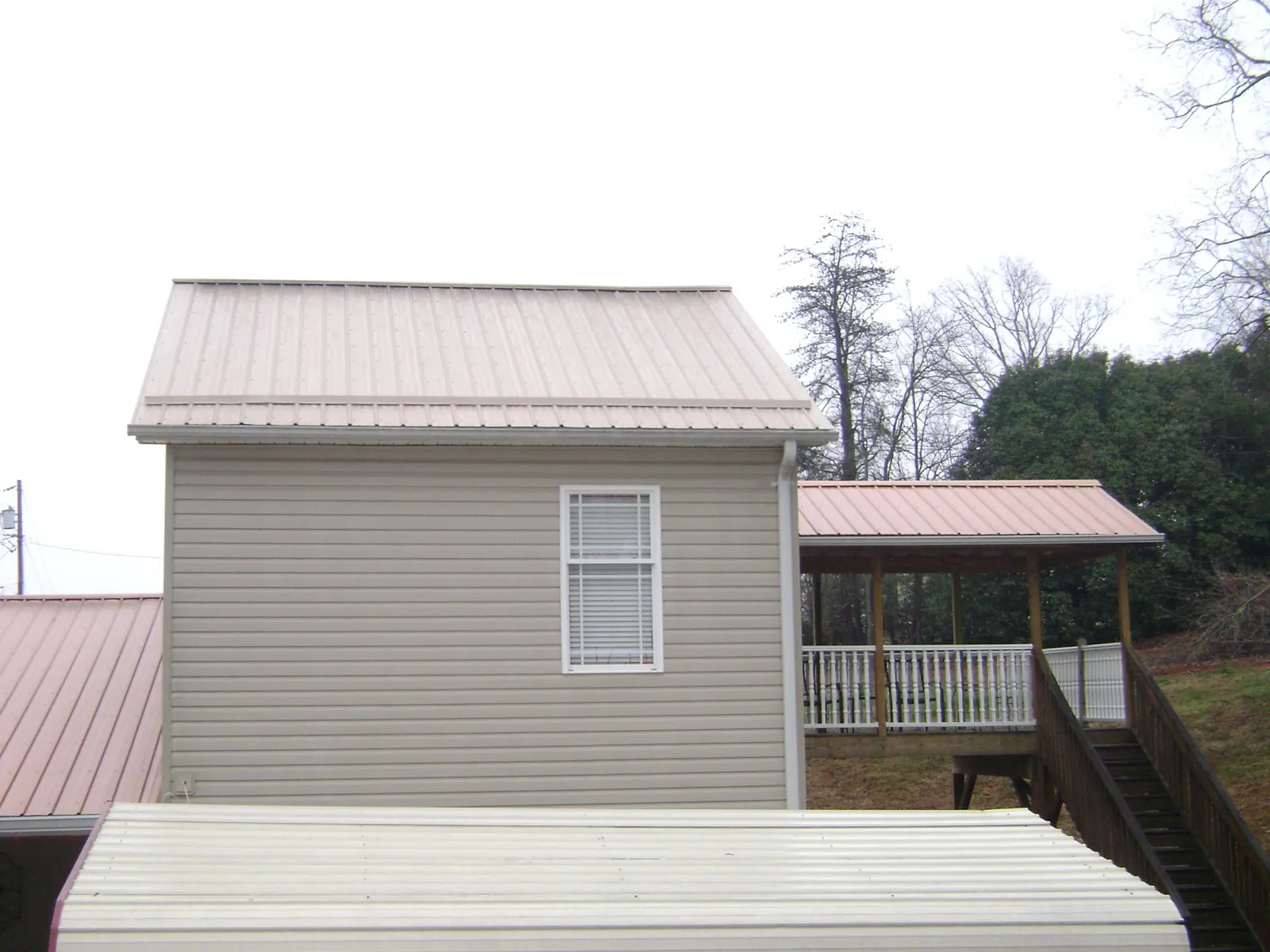 Tan metal roofs on a two story addition and attached porch, from a Roof Replacement job in Amador City