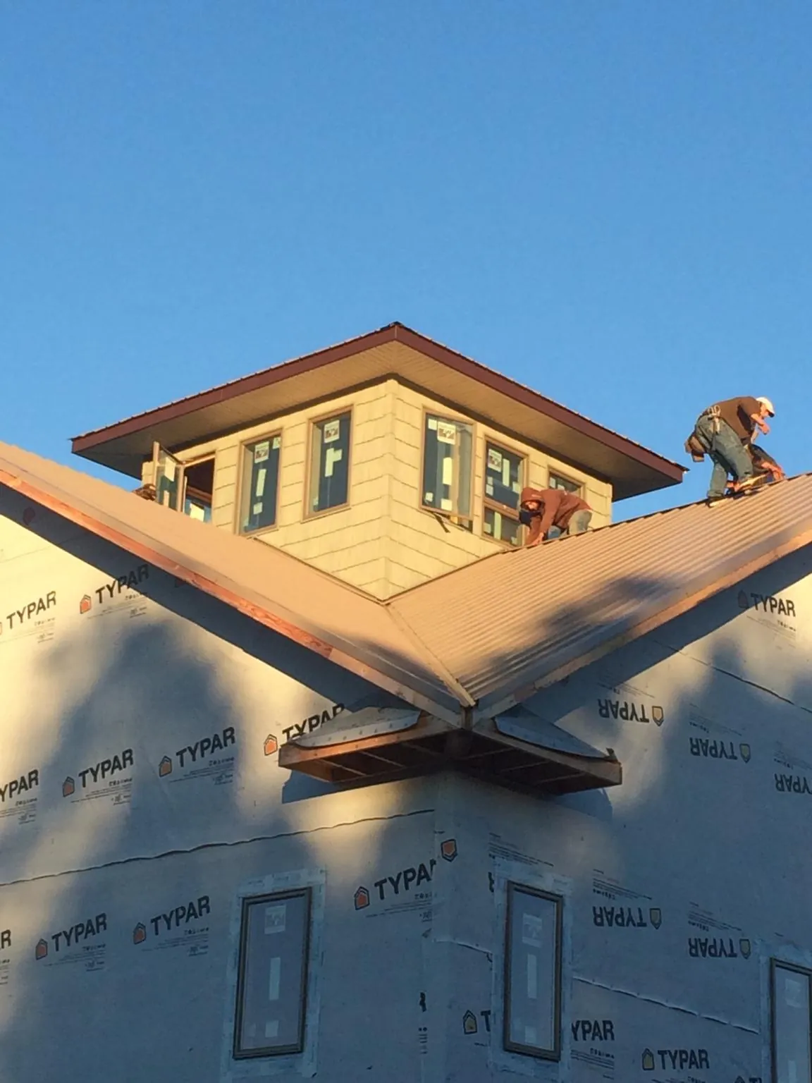 Roofers working around a rooftop cupola on a new metal roof at sunset — Roof Waterproofing in Amador City by Roofing Brothers